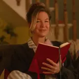 Bridget Jones uśmiecha się, czytając książkę. To idealny moment na recenzję książki "Dziennik Bridget Jones".
