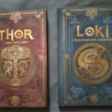 Dwie książki z motywami nordyckimi: "Thor i moc Mjolnira" z młotem, oraz "Loki i przepowiednia Ragnarök" z wężem. Poznaj symbole nordyckie i ich znaczenie.