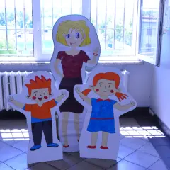 Kiedy śmieje się dziecko, świat staje się lepszy." - Korczak. Postacie z papieru: pani i dwoje dzieci, stoją przy oknie.