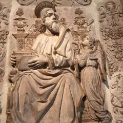 Rzeźba przedstawia św. Mateusza z aniołem, symbolizując znaczenie symboli ewangelistów. W tle widoczne ornamenty.