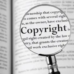 Lupa powiększa słowo "Copyright" w książce, pokazując, jak zapisać cytat zgodnie z prawem.