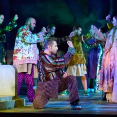 Scena z "Romeo i Julii" w angielskiej recenzji. Aktorzy w barwnych strojach tańczą na scenie.