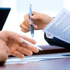 Dwie osoby omawiają dokumenty, ustalając, jaką umowę cywilnoprawną powinno zawrzeć wydawnictwo z autorem książki.