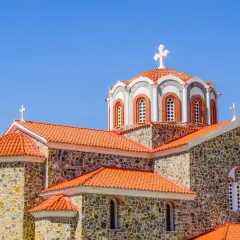 Kamienna cerkiew z pomarańczowym dachem i krzyżami na kopułach. Symbolika religijna i ich znaczenie widoczne w architekturze.