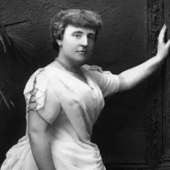 Frances Hodgson Burnett, autorka książki "Tajemniczy ogród", na czarno-białym zdjęciu pozuje w eleganckiej sukni i naszyjniku.
