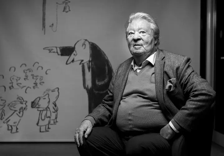 Starszy mężczyzna siedzi przed rysunkiem z Mikołajkiem. Czy wiesz, jak nazywa się autor książki Mikołajek?