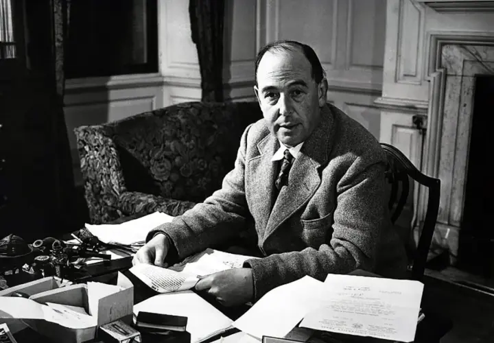 C.S. Lewis, autor "Opowieści z Narnii", siedzi przy biurku, otoczony papierami i atramentem.