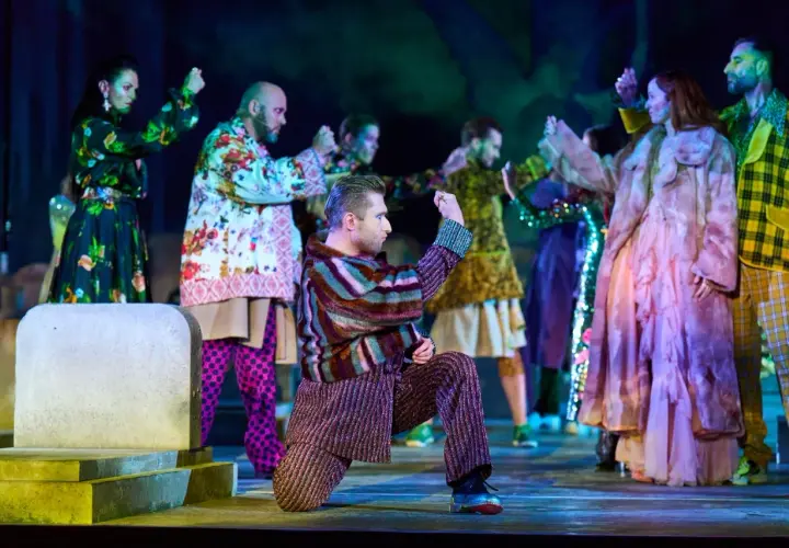 Scena z "Romeo i Julii" w angielskiej recenzji. Aktorzy w barwnych strojach tańczą na scenie.