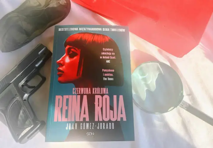 Recenzja książki "Czerwona Królowa" Juana Gómeza-Jurado. Obok leży pistolet i lupa, sugerując kryminalną fabułę.