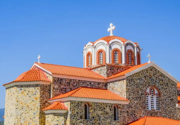 Kamienna cerkiew z pomarańczowym dachem i krzyżami na kopułach. Symbolika religijna i ich znaczenie widoczne w architekturze.