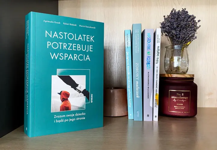 Recenzja książki o wychowaniu: "Nastolatek potrzebuje wsparcia". Na półce obok inne poradniki dla rodziców i świeca.
