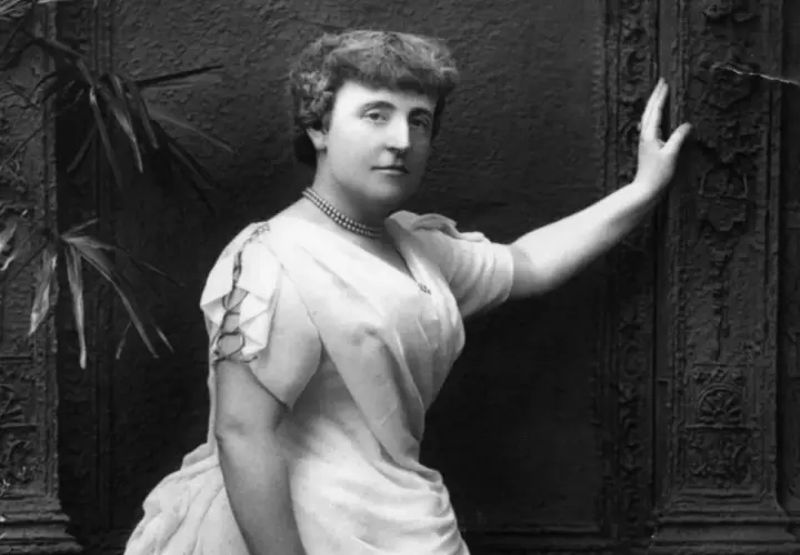 Frances Hodgson Burnett, autorka książki "Tajemniczy ogród", na czarno-białym zdjęciu pozuje w eleganckiej sukni i naszyjniku.