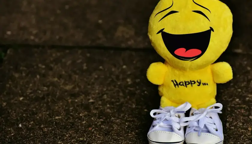 Żółta maskotka z napisem "Happy..." na brzuchu i uśmiechem od ucha do ucha. Idealna, by przypomnieć o cytatach, które poprawiają humor.