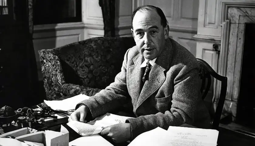 C.S. Lewis, autor "Opowieści z Narnii", siedzi przy biurku, otoczony papierami i atramentem.