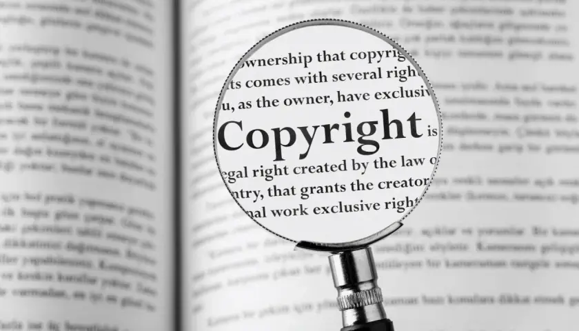 Lupa powiększa słowo "Copyright" w książce, pokazując, jak zapisać cytat zgodnie z prawem.