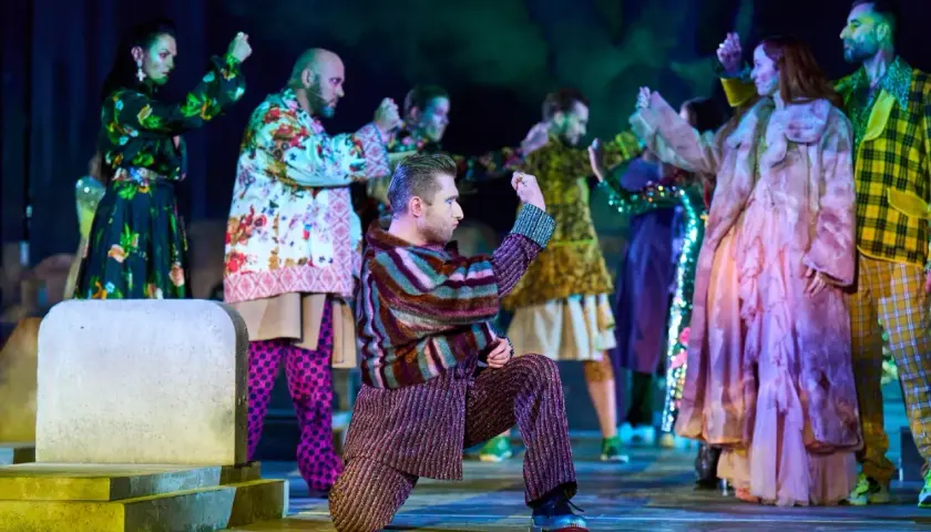 Scena z "Romeo i Julii" w angielskiej recenzji. Aktorzy w barwnych strojach tańczą na scenie.