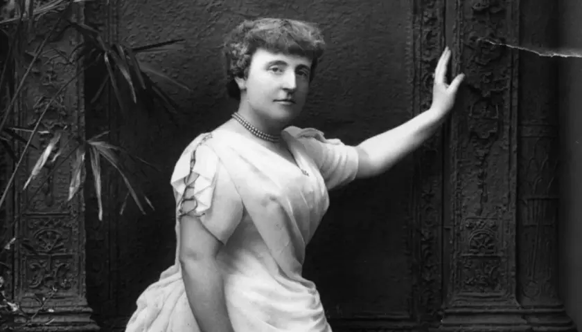 Frances Hodgson Burnett, autorka książki "Tajemniczy ogród", na czarno-białym zdjęciu pozuje w eleganckiej sukni i naszyjniku.