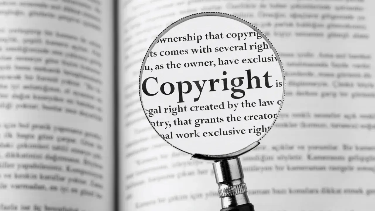 Lupa powiększa słowo "Copyright" w książce, pokazując, jak zapisać cytat zgodnie z prawem.