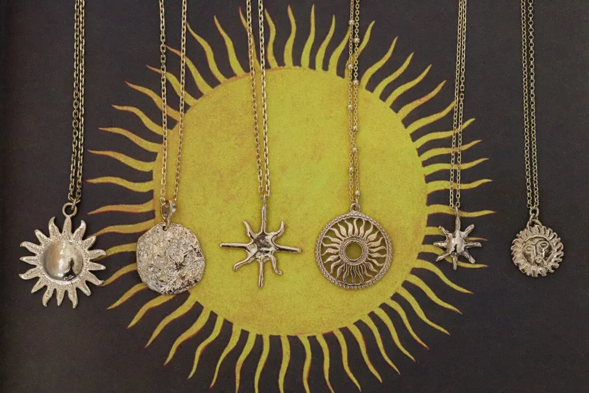 Pięć złotych naszyjników z motywem słońca. Symbol słońca znaczenie: życie, moc, energia.