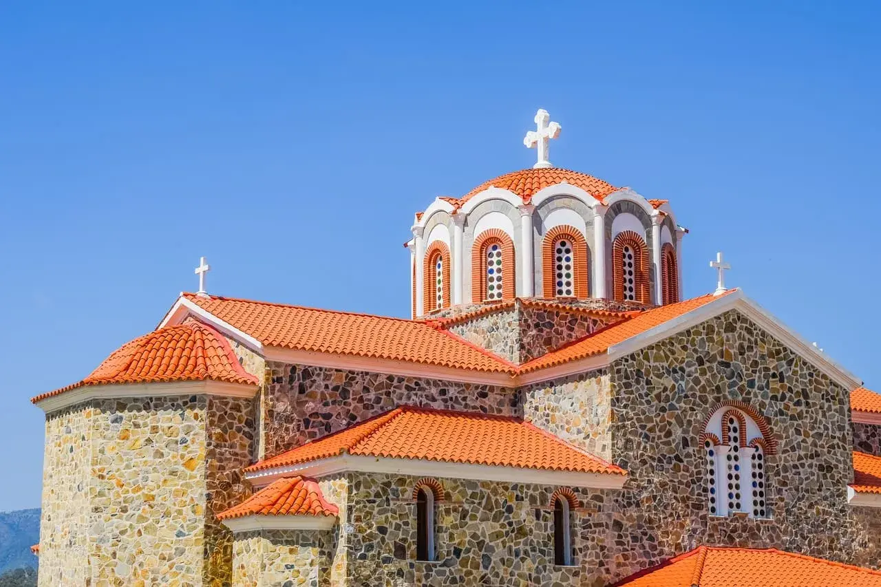 Kamienna cerkiew z pomarańczowym dachem i krzyżami na kopułach. Symbolika religijna i ich znaczenie widoczne w architekturze.