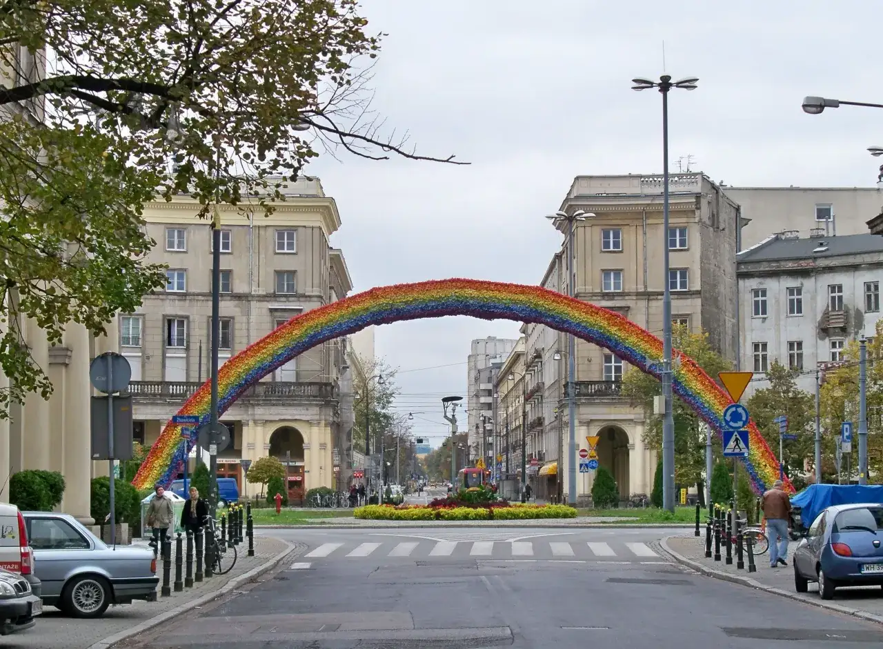 Tęcza na ulicy, symbol nadziei i różnorodności, rozciąga się nad skrzyżowaniem.